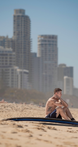 man sitting on a beach with city scape in background